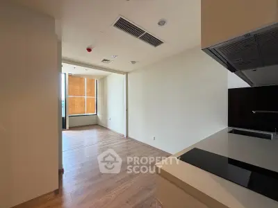 Modern open-plan apartment with sleek kitchen and wooden flooring, featuring large windows for natural light.