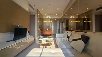 Modern living room with stylish decor and ample natural light, featuring a cozy sofa and sleek TV setup.