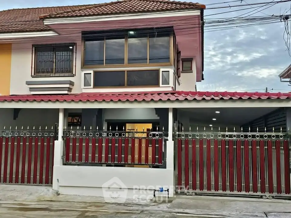 Charming two-story house with red tile roof and gated entrance, perfect for family living.