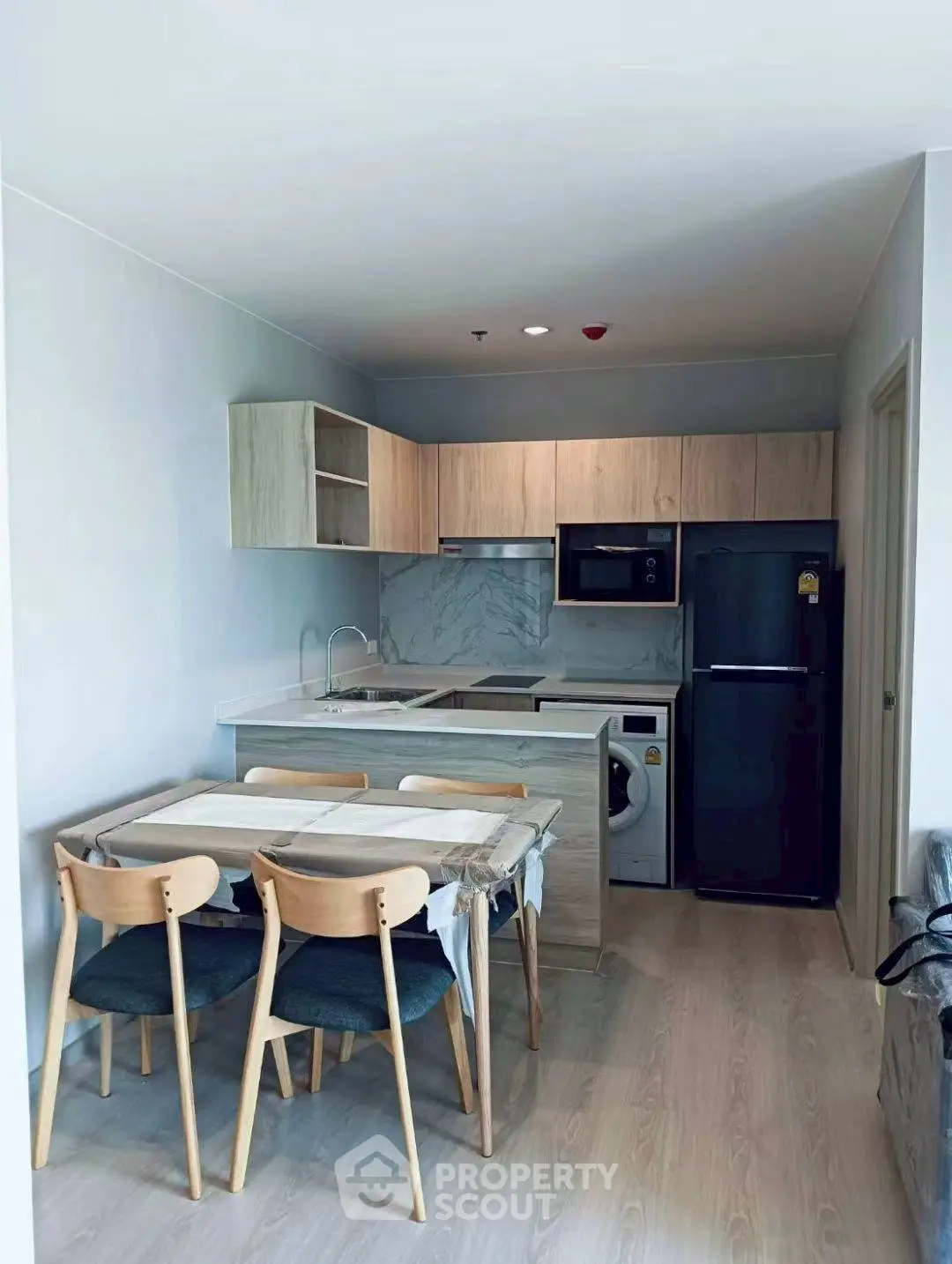 Modern kitchen with dining area, featuring sleek appliances and stylish wooden cabinetry.