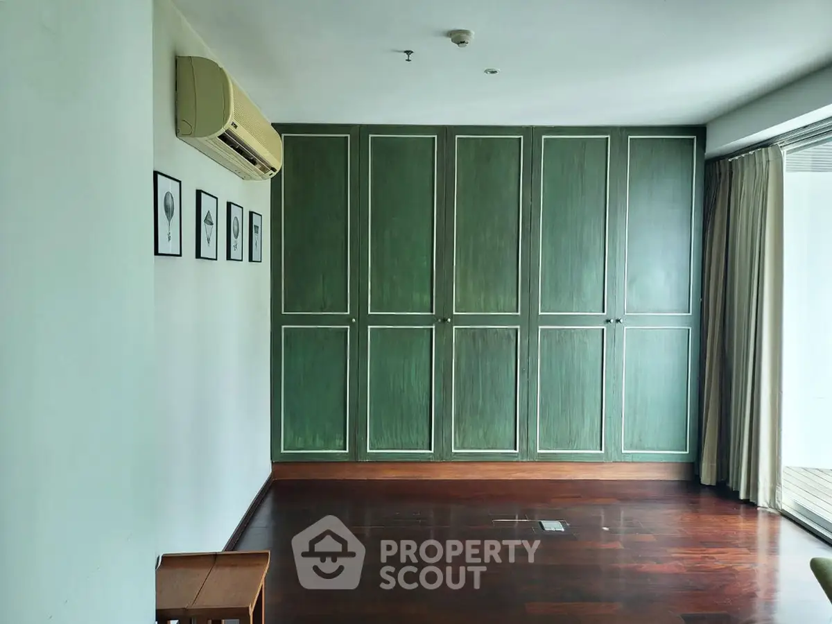 Spacious room with elegant green cabinetry and hardwood floors, perfect for stylish living.