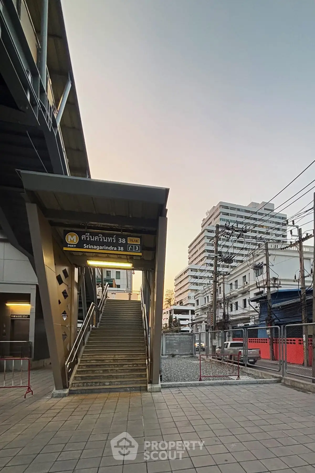 Modern urban entrance to Sinakharinwirot 38 with cityscape backdrop at sunset.