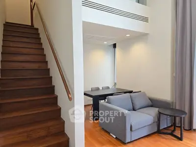 Modern duplex living room with wooden staircase and cozy seating area