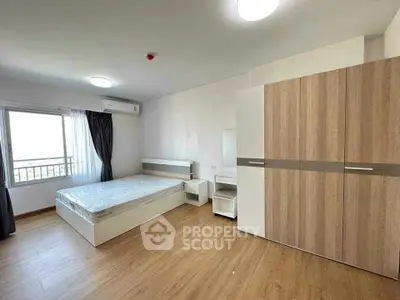 Spacious bedroom with modern furnishings and large window offering natural light.