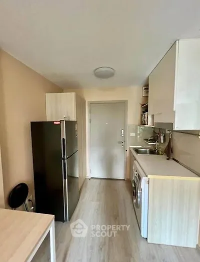 Modern kitchen with sleek appliances and compact design, featuring a fridge and washing machine.