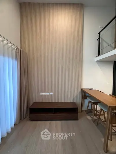 Modern living room with high ceiling and stylish wooden furniture in a contemporary apartment.