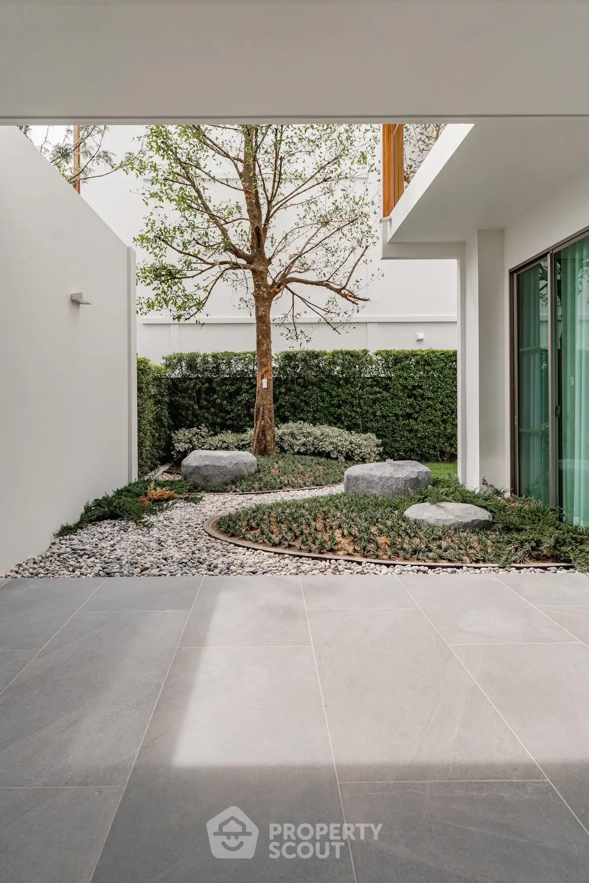 Modern minimalist garden with stone pathway and lush greenery in a contemporary home.