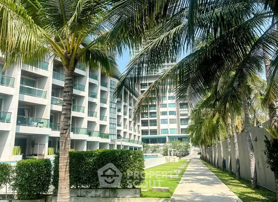 Luxurious modern apartment complex with palm-lined pathway and lush greenery