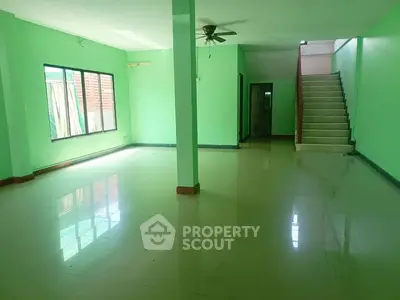 Spacious green-painted interior with staircase and ceiling fan, ideal for customization.