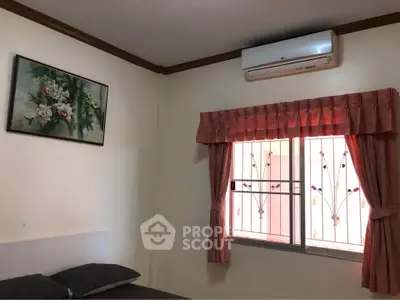 Cozy bedroom with air conditioning and floral decor, featuring a window with decorative bars and pink curtains.