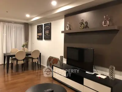 Elegant living room with modern decor and dining area, featuring stylish furniture and warm lighting.