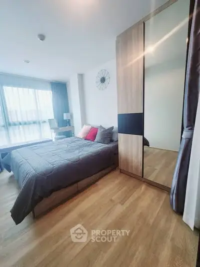 Modern bedroom with large window and stylish decor in a contemporary apartment.