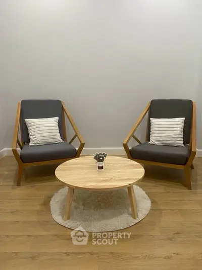 Minimalist living room with modern chairs and round wooden table on a cozy rug.