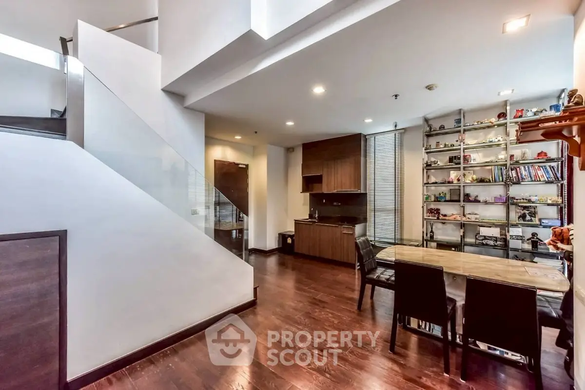 Modern open-plan living area with sleek kitchen and stylish dining space, featuring elegant wooden flooring and contemporary decor.