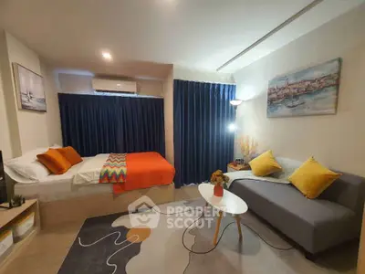 Cozy studio apartment with modern decor, featuring a bed, sofa, and stylish rug.