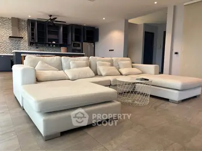 Spacious modern living room with plush white sectional sofa and open kitchen layout.