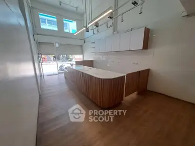 Modern kitchen with sleek wooden island and high ceilings in a bright open space.