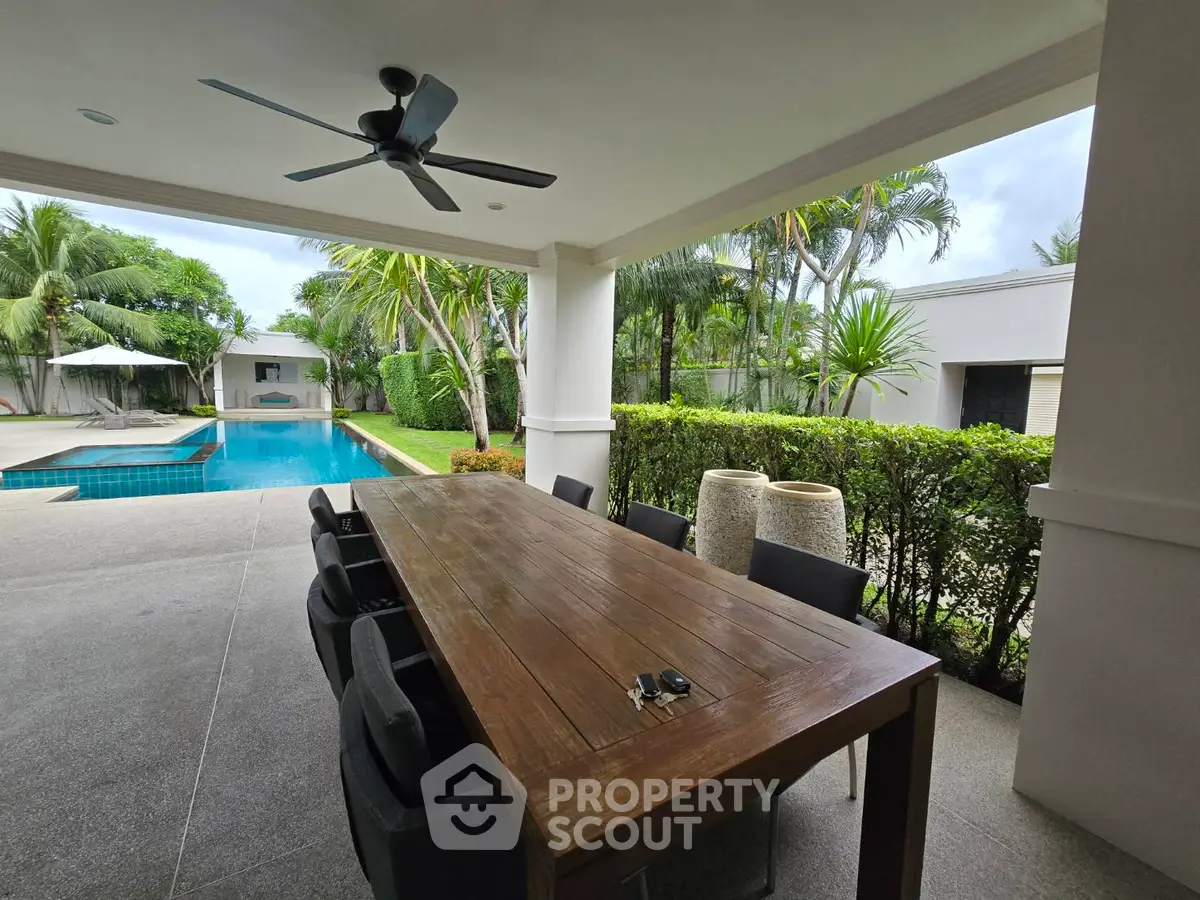 Luxurious outdoor patio with pool view and elegant dining area, perfect for entertaining.