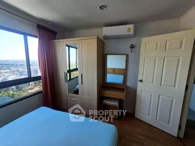 Cozy bedroom with city view, featuring a wardrobe, vanity, and air conditioning for comfortable living.