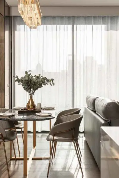 Elegant modern living room with dining area, featuring chic furniture and large windows for natural light.