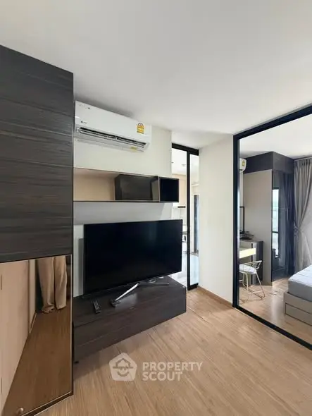 Modern living room with sleek design and large TV, featuring wooden flooring and stylish decor.