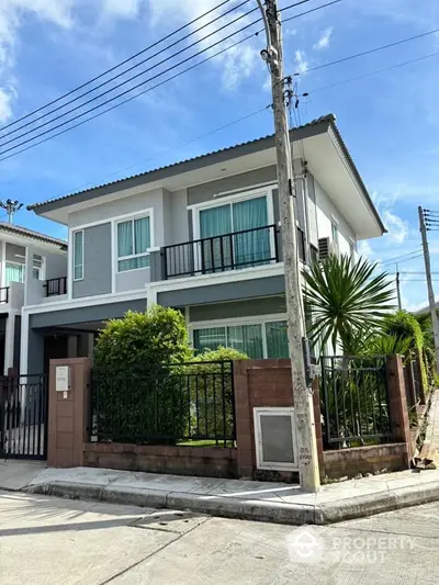 Modern two-story house with lush garden and secure fencing in a serene neighborhood.