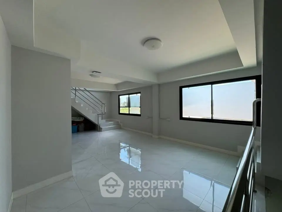 Spacious modern living room with large windows and sleek staircase