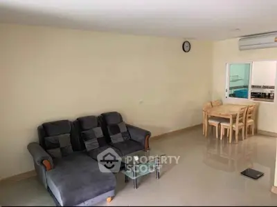 Spacious living room with modern furniture and dining area in open layout apartment.
