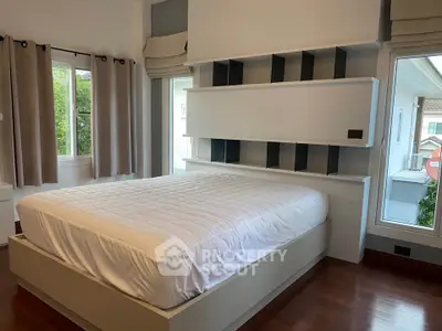 Spacious bedroom with modern design and large windows offering natural light and garden view.