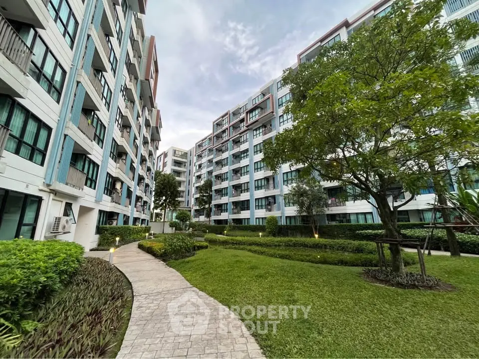 Modern apartment complex with lush green garden and paved walkway