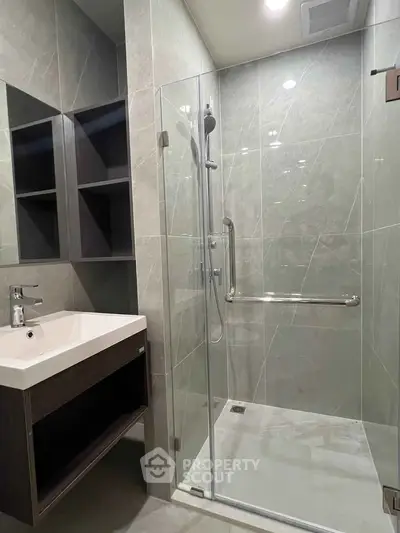 Modern bathroom with sleek glass shower and stylish sink in contemporary apartment.