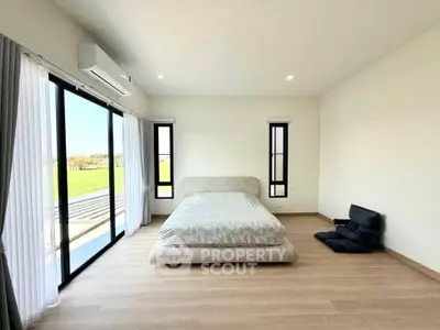 Spacious bedroom with large windows and serene outdoor view, featuring minimalist decor and natural light.