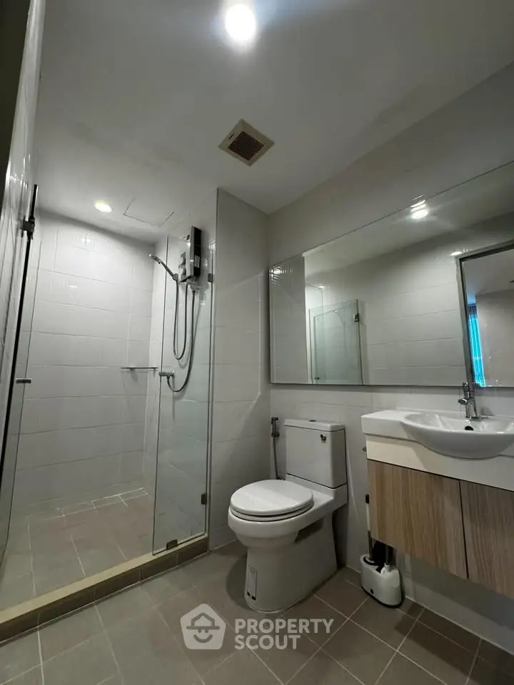 Modern bathroom with glass shower and sleek fixtures in contemporary apartment.