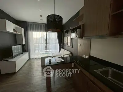 Modern living room with open kitchen, featuring sleek furniture and large windows for natural light.