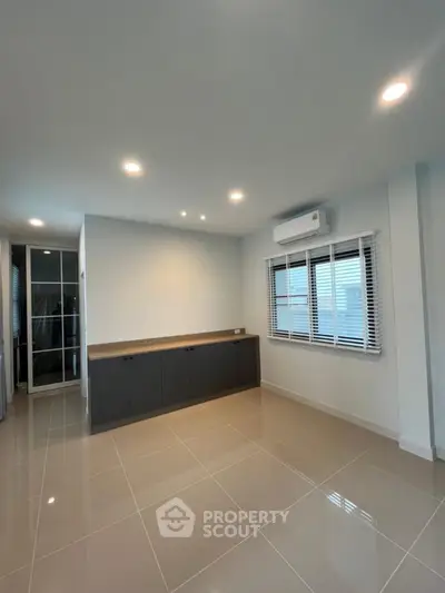 Spacious modern living room with sleek tile flooring and ample natural light.