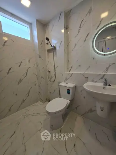 Modern bathroom with marble tiles and circular mirror