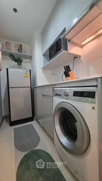 Modern kitchen with sleek appliances and efficient layout, featuring a washing machine and microwave.