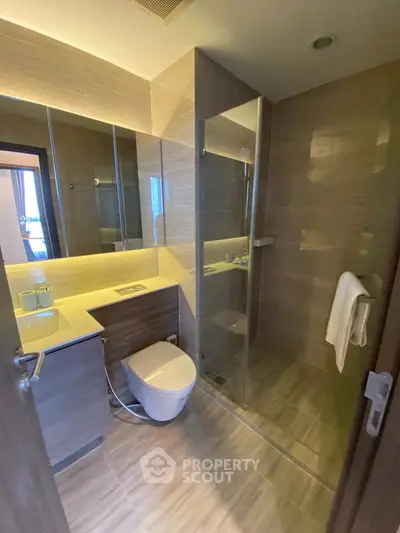 Modern bathroom with glass shower and sleek fixtures in contemporary apartment.
