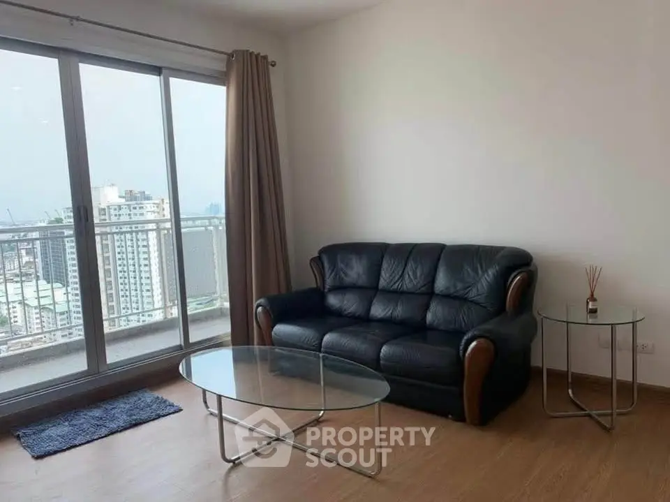 Modern living room with leather sofa and glass coffee table, featuring a stunning city view from the balcony.