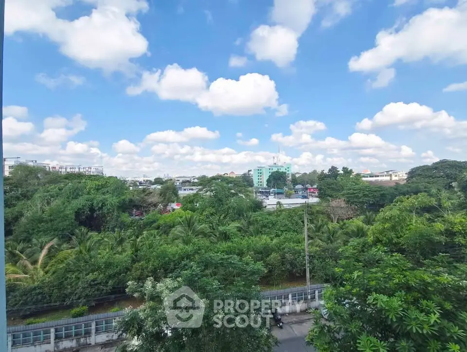 Stunning panoramic view of lush greenery and cityscape under a vibrant blue sky with fluffy clouds.