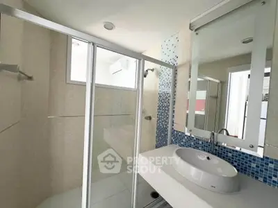 Modern bathroom with glass shower and stylish sink in a bright apartment.