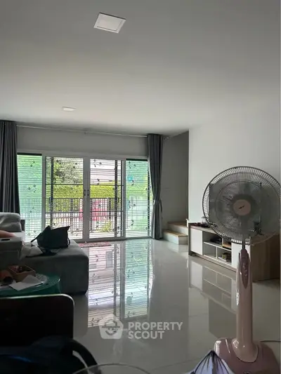 Spacious living room with modern decor and large windows offering natural light and garden view.