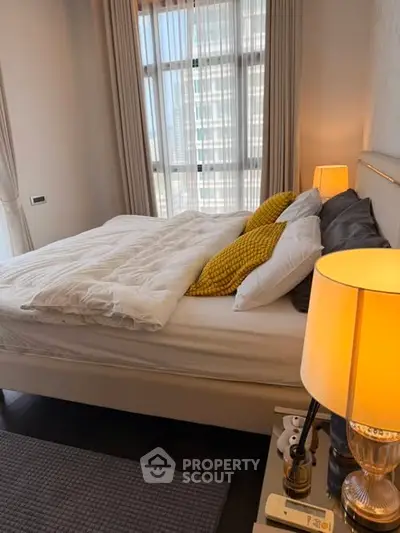 Cozy bedroom with modern decor and large window offering natural light.