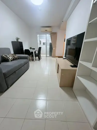 Spacious living room with modern decor and large TV, perfect for relaxation and entertainment.