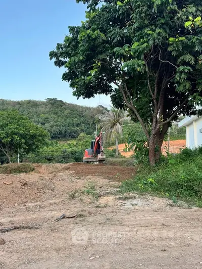 Scenic land plot with lush greenery and construction equipment, ideal for development.