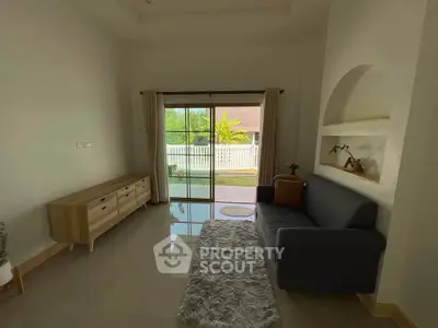 Spacious living room with modern furniture and garden view through sliding doors.