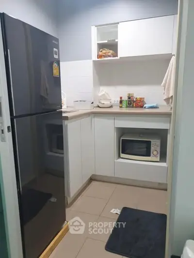 Compact kitchen with modern appliances and sleek cabinetry in a cozy apartment.