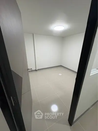 Minimalist empty room with tiled floor and modern lighting, ideal for storage or utility use.