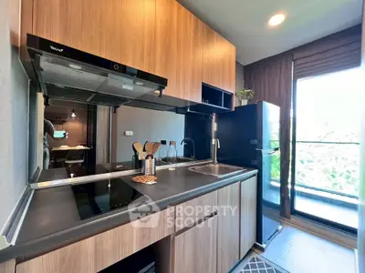 Modern kitchen with sleek wooden cabinets and large window offering natural light.