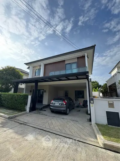 Modern two-story house with carport and lush greenery in a serene neighborhood.